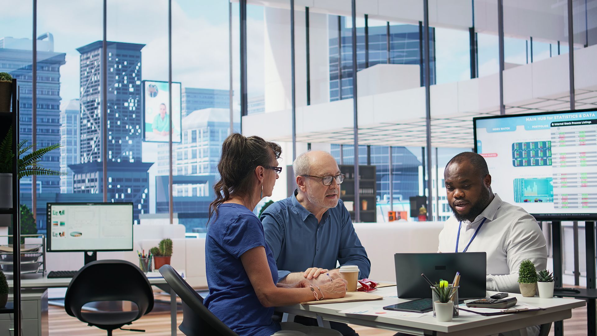 A group of people are sitting around a table looking at a laptop computer.