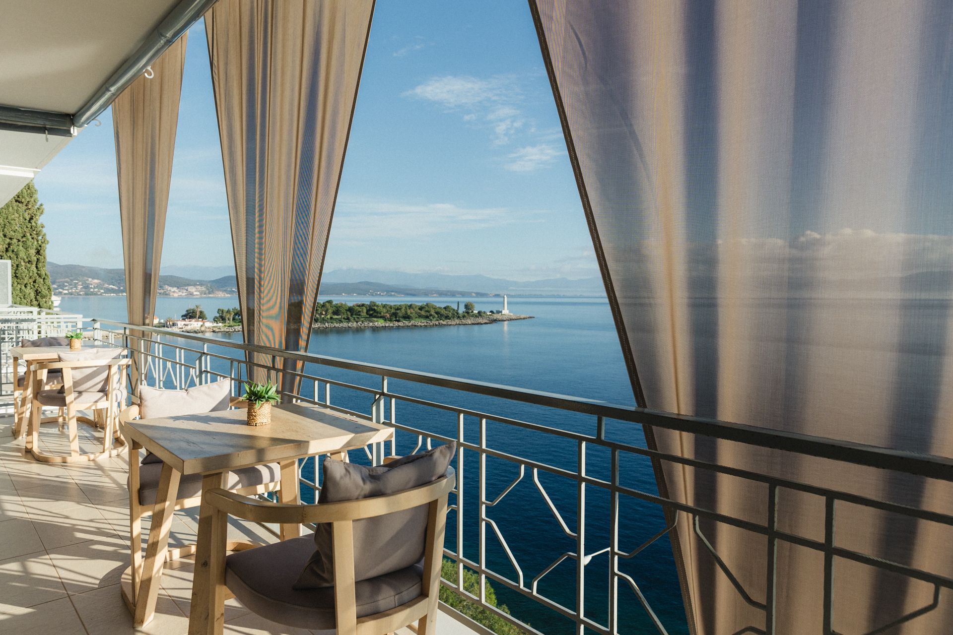 A balcony with a table and chairs overlooking the ocean.