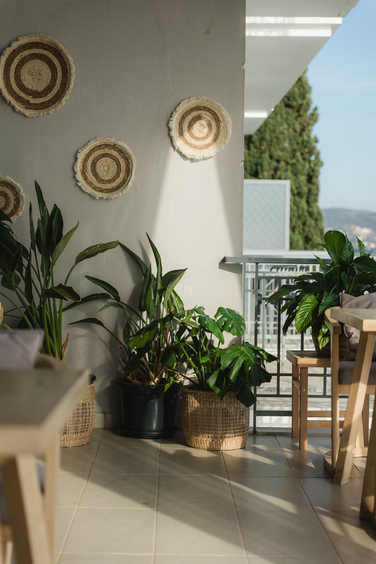 A balcony with lots of potted plants and wicker baskets on the wall.