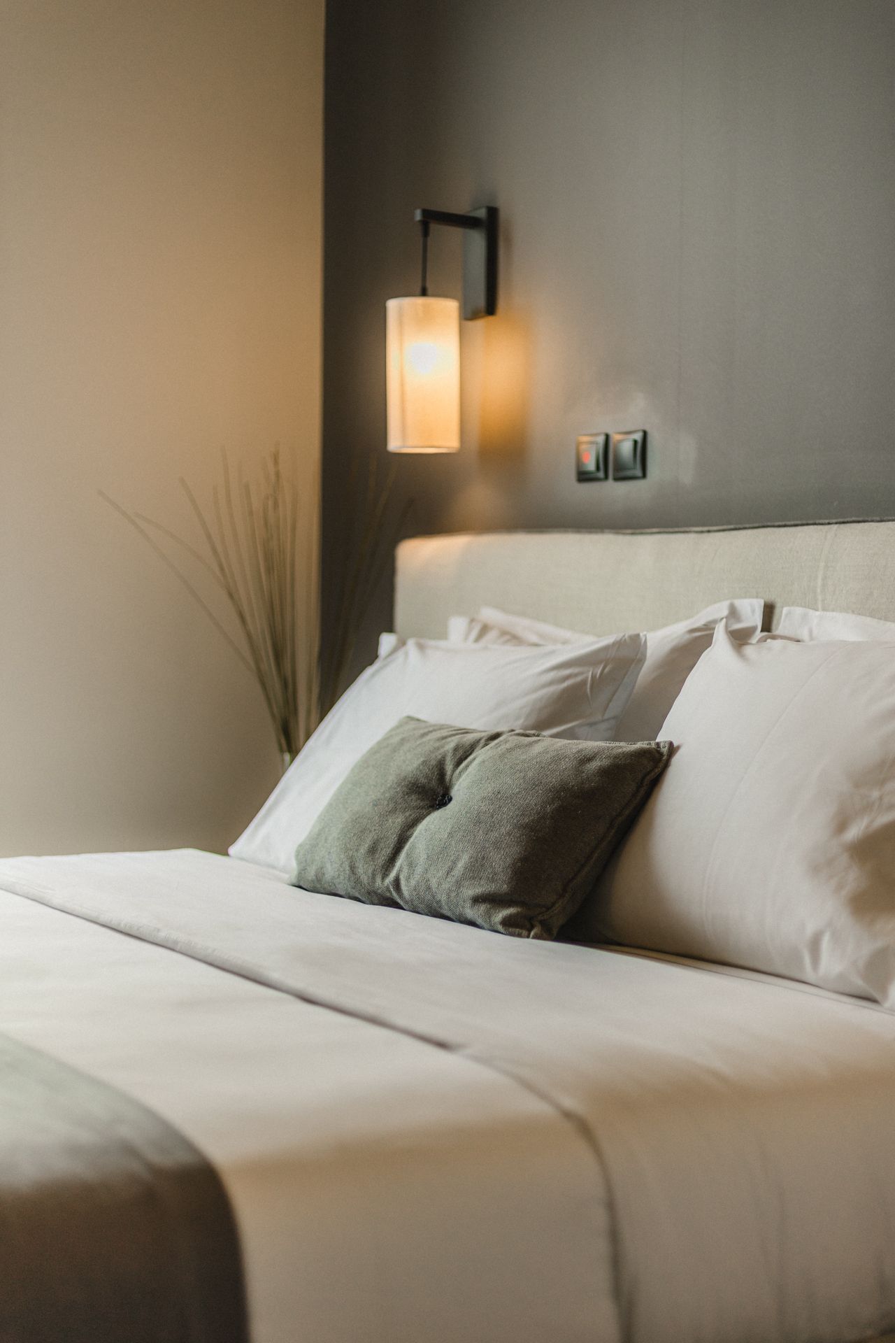A bed with white sheets and pillows in a hotel room.