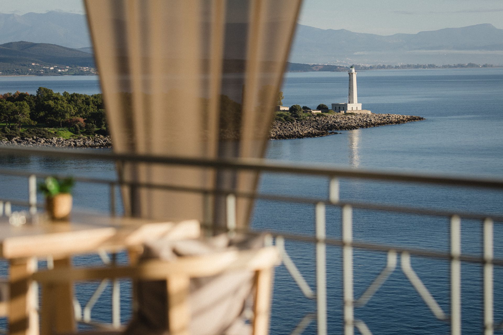 A balcony overlooking the ocean with a lighthouse in the distance.
