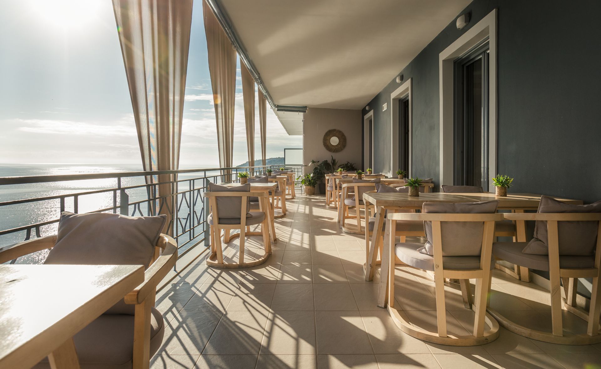 A restaurant with tables and chairs on a balcony overlooking the ocean.