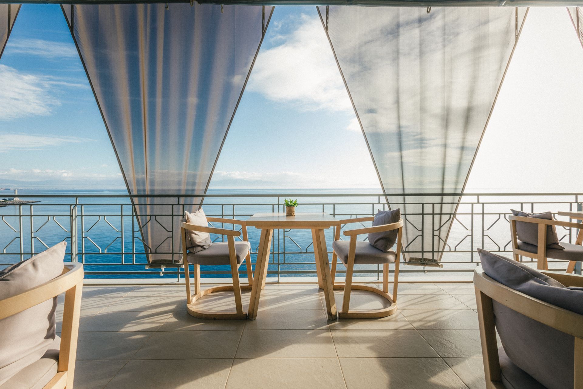 A balcony with a table and chairs overlooking the ocean.