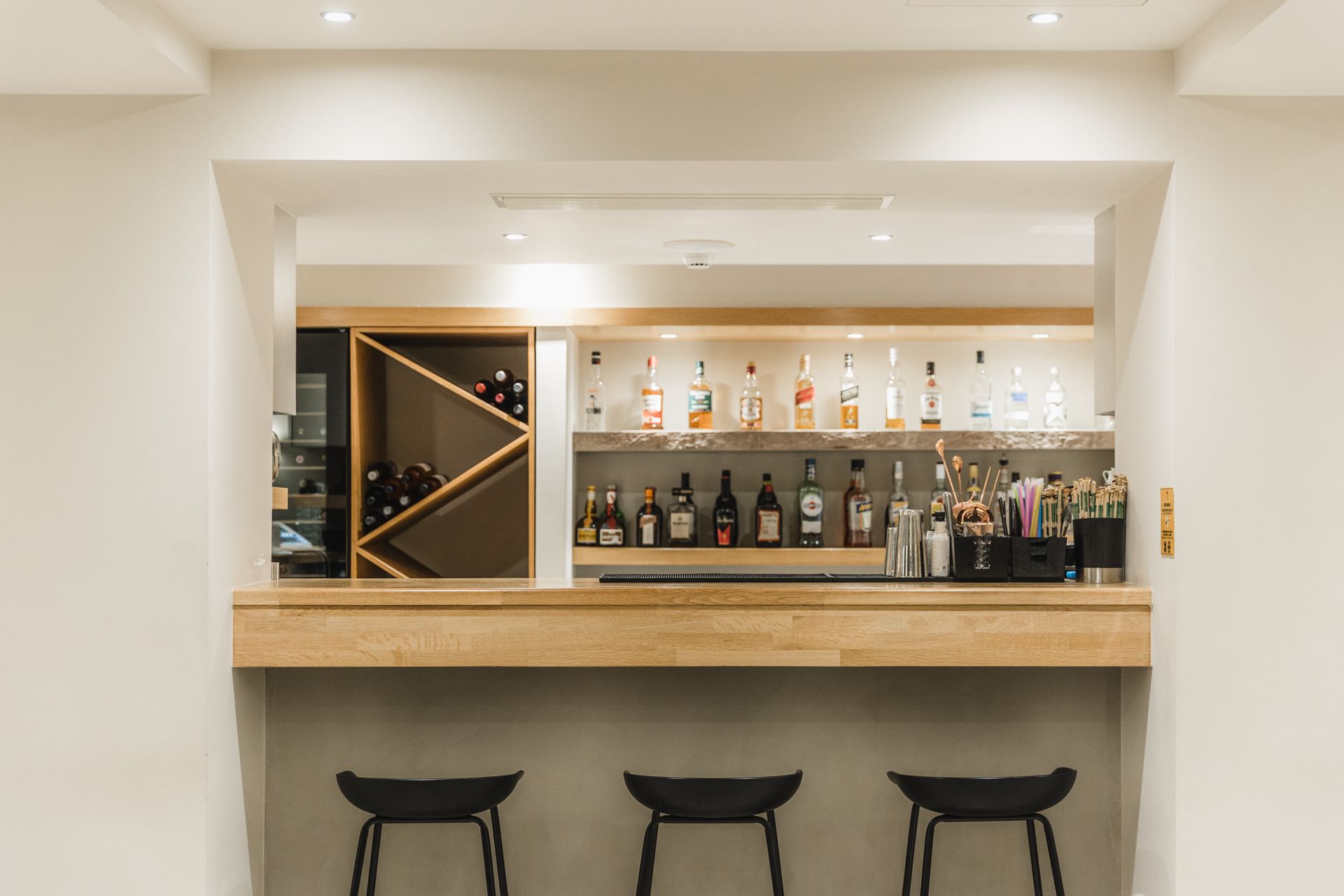 A bar with stools and bottles of alcohol on the shelf.