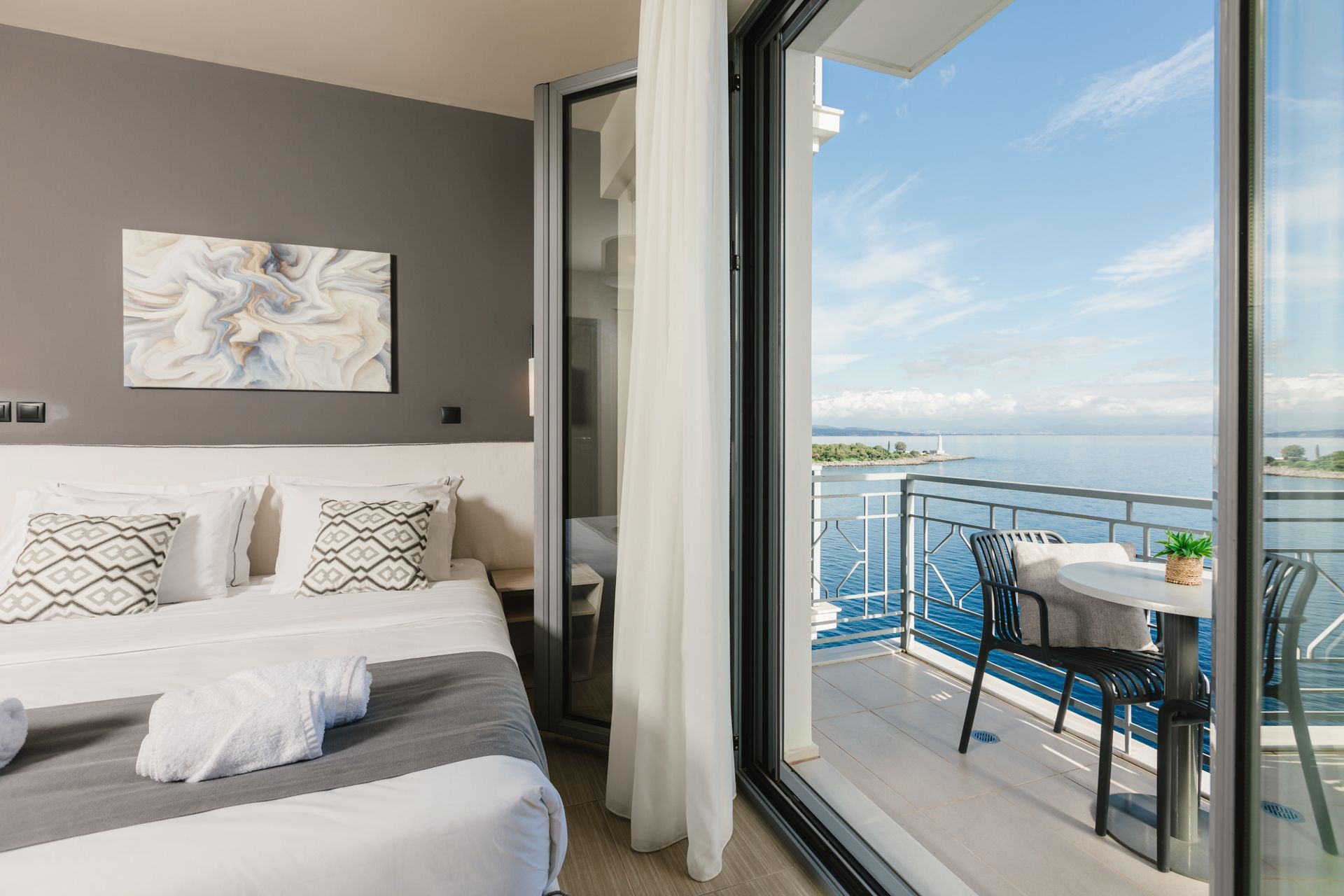 A hotel room with a bed and a balcony overlooking the ocean.