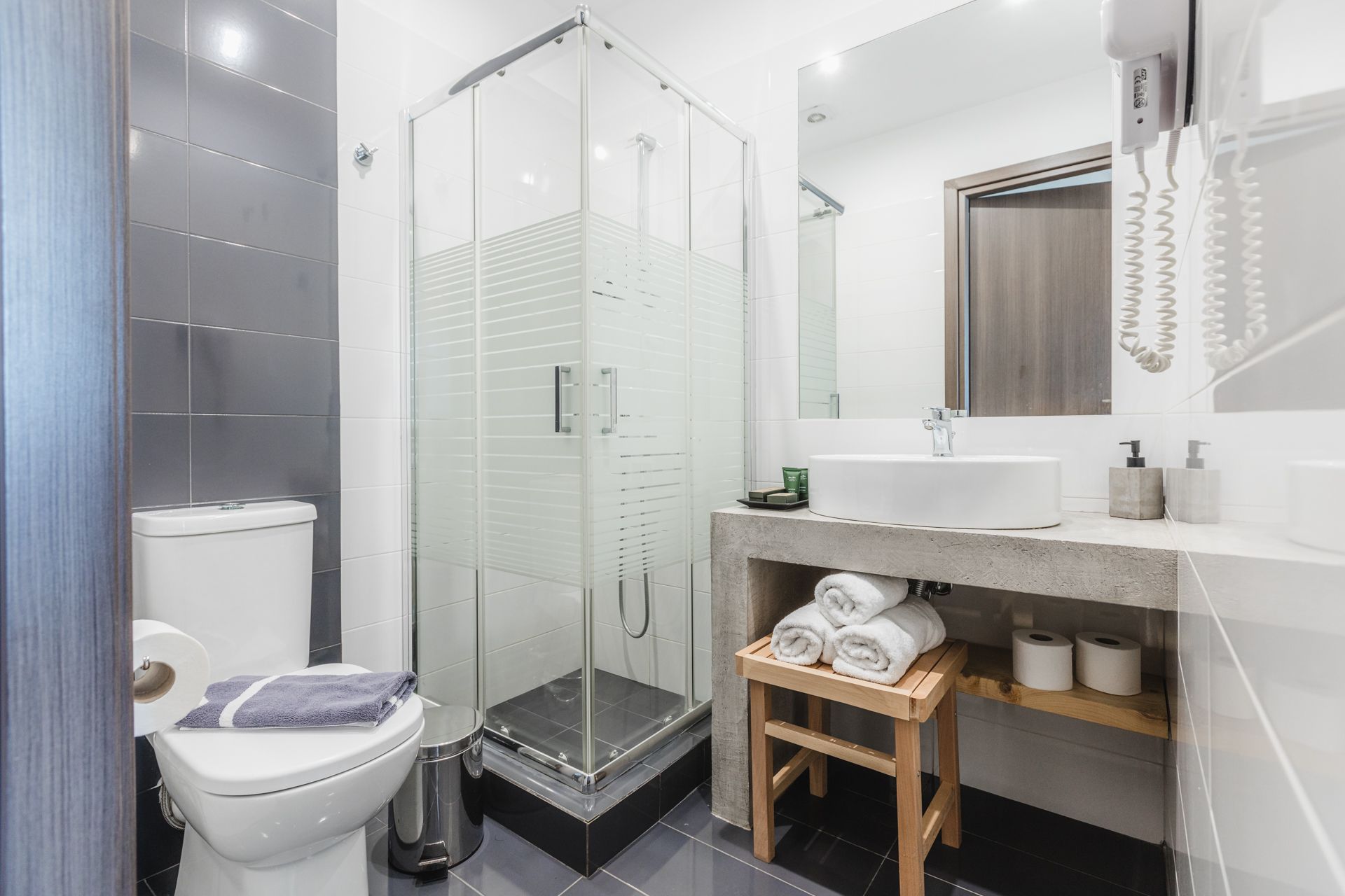 A bathroom with a toilet , sink , shower and mirror.