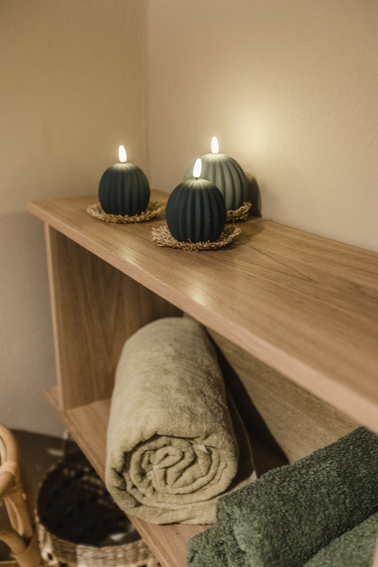 A wooden shelf with towels and candles on it.