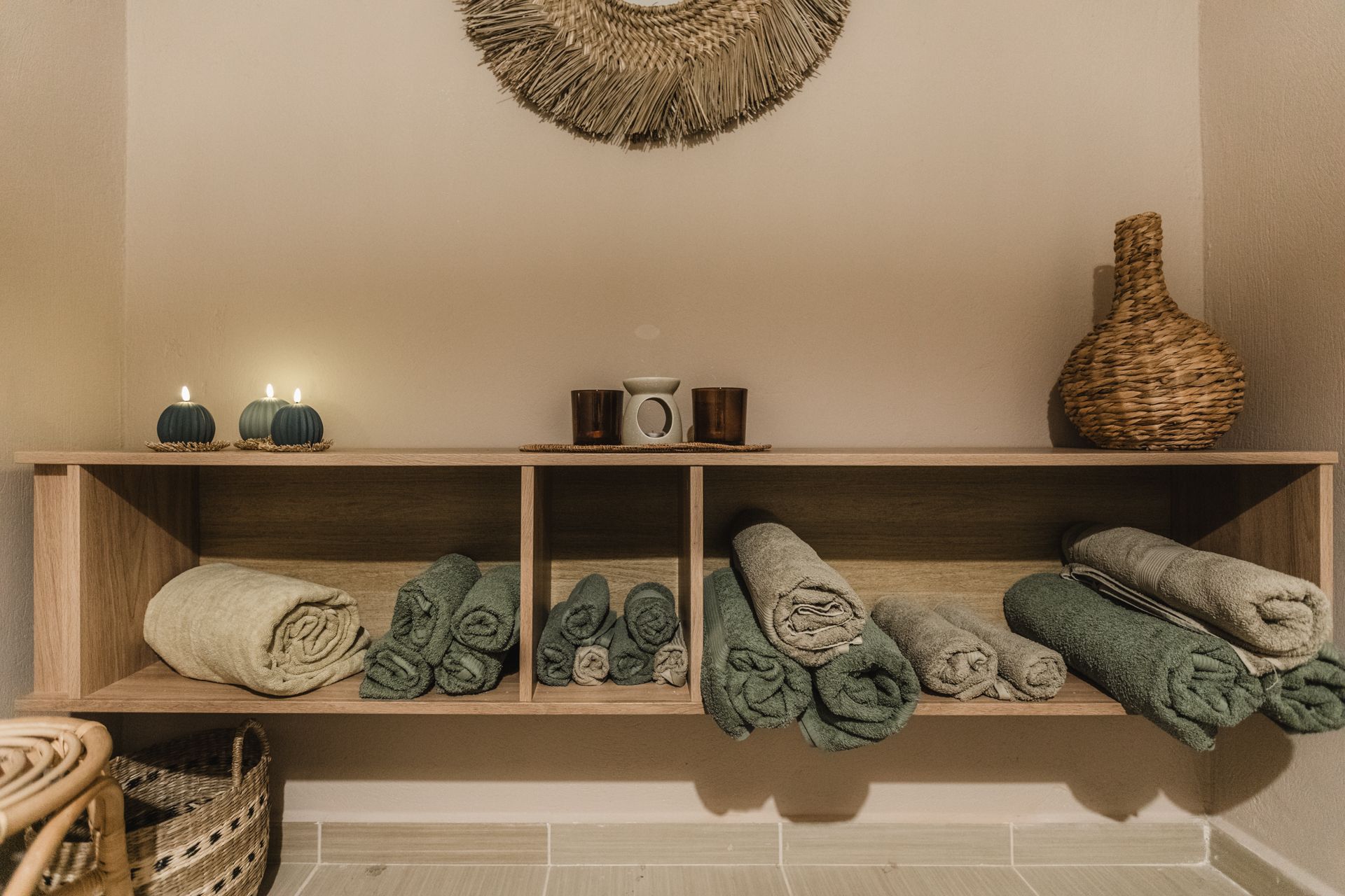 A shelf filled with towels and candles in a room.