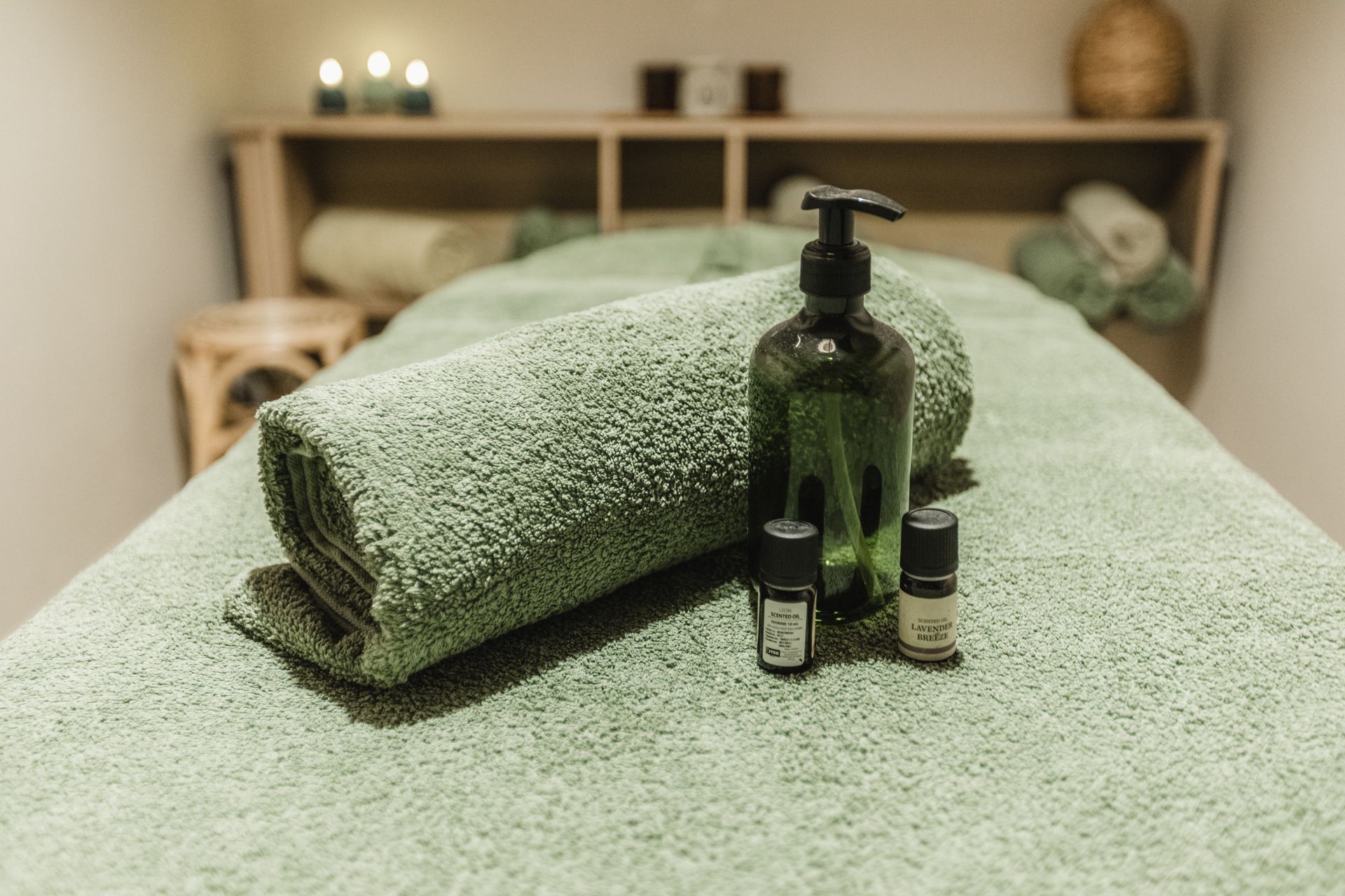 A massage table with towels and essential oils on it.