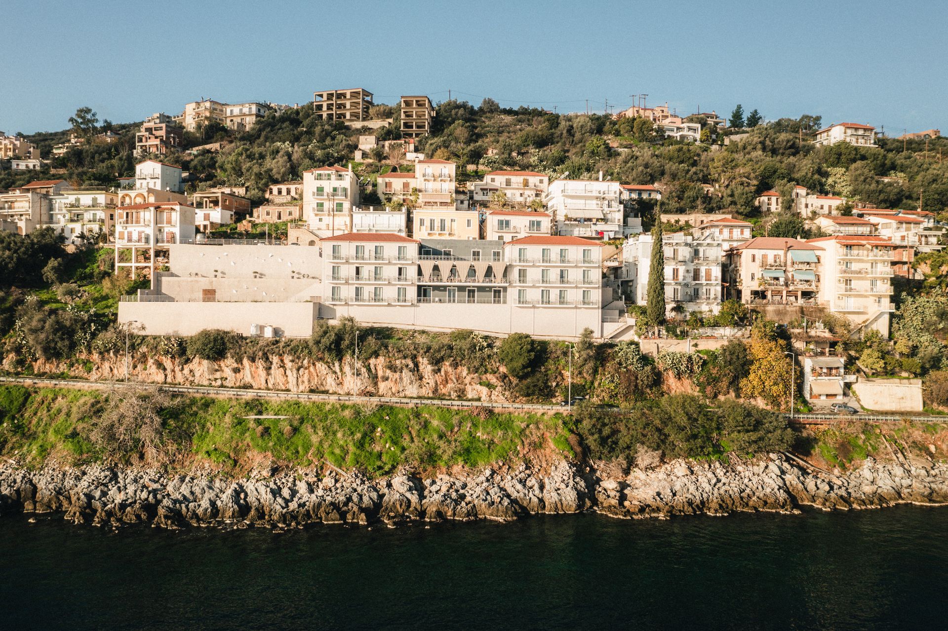 A large building is sitting on top of a hill next to a body of water.