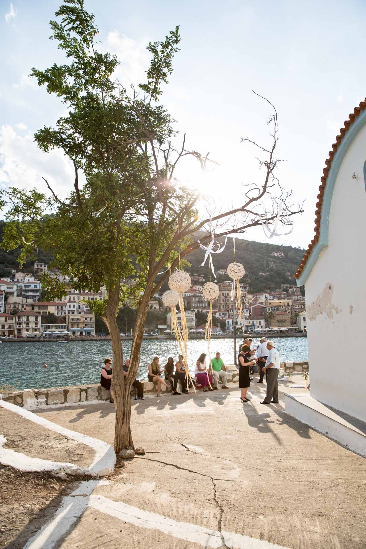 A group of people are sitting under a tree near a body of water.