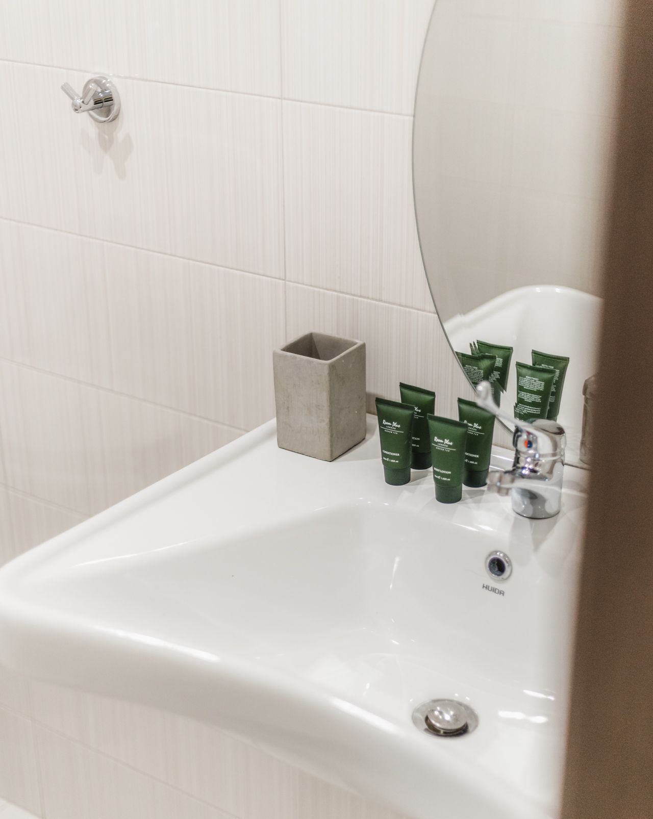 A bathroom sink with green tubes of lotion on it