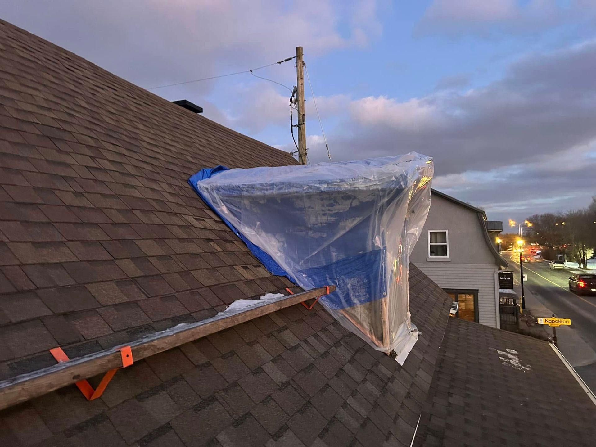Un toit avec une bâche bleue dessus.