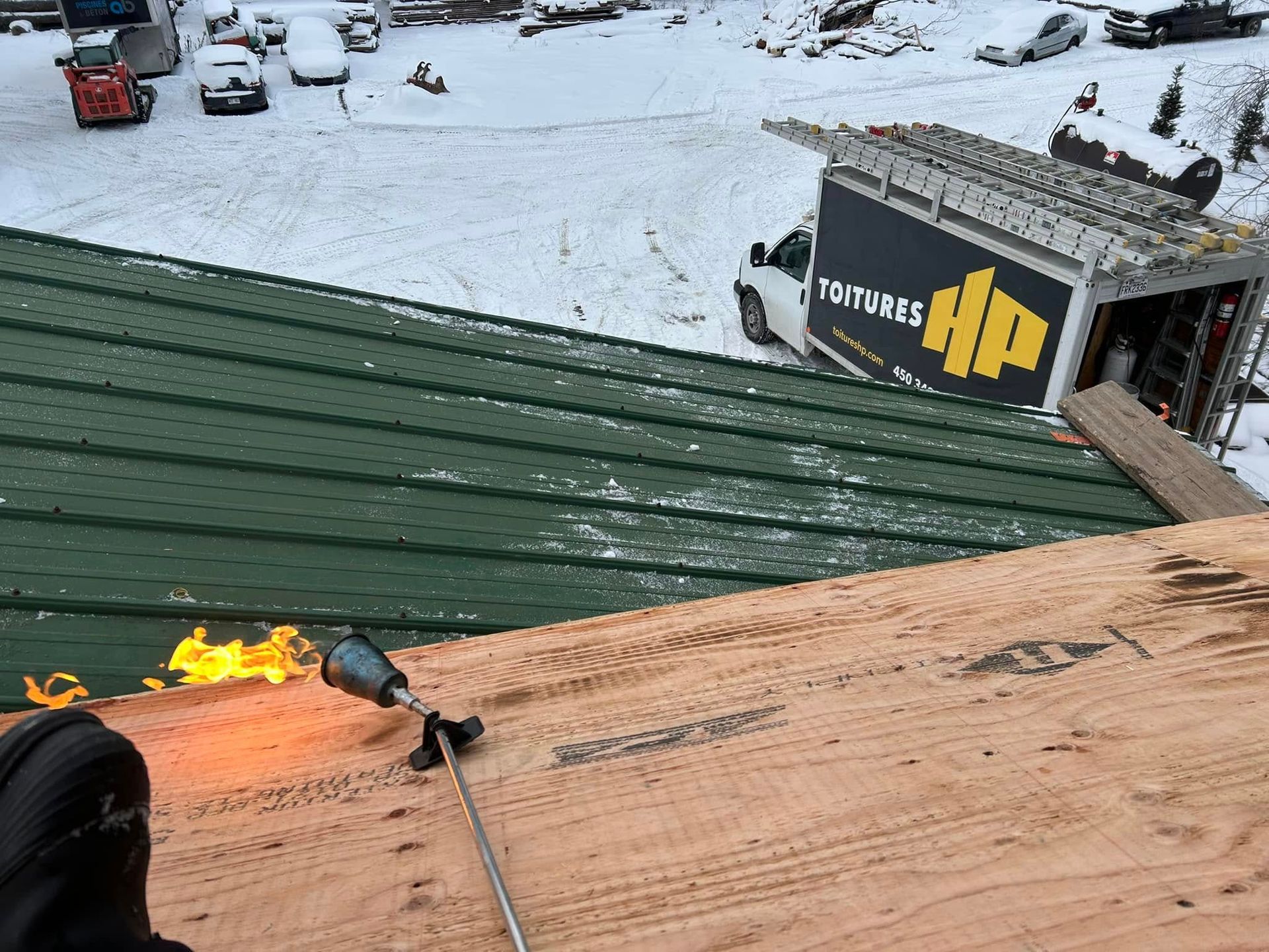 Une personne tient une torche au sommet d'un toit vert.