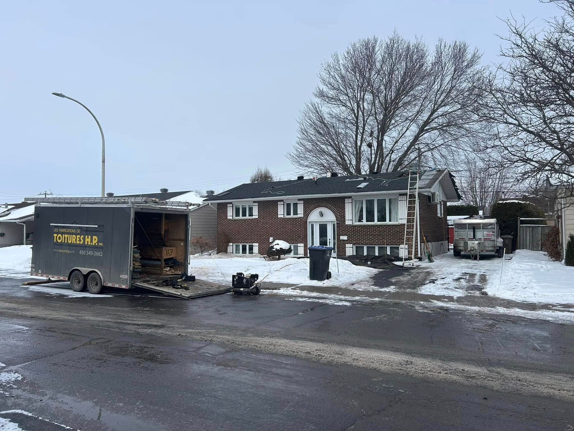 Une remorque est garée devant une maison sous la neige.