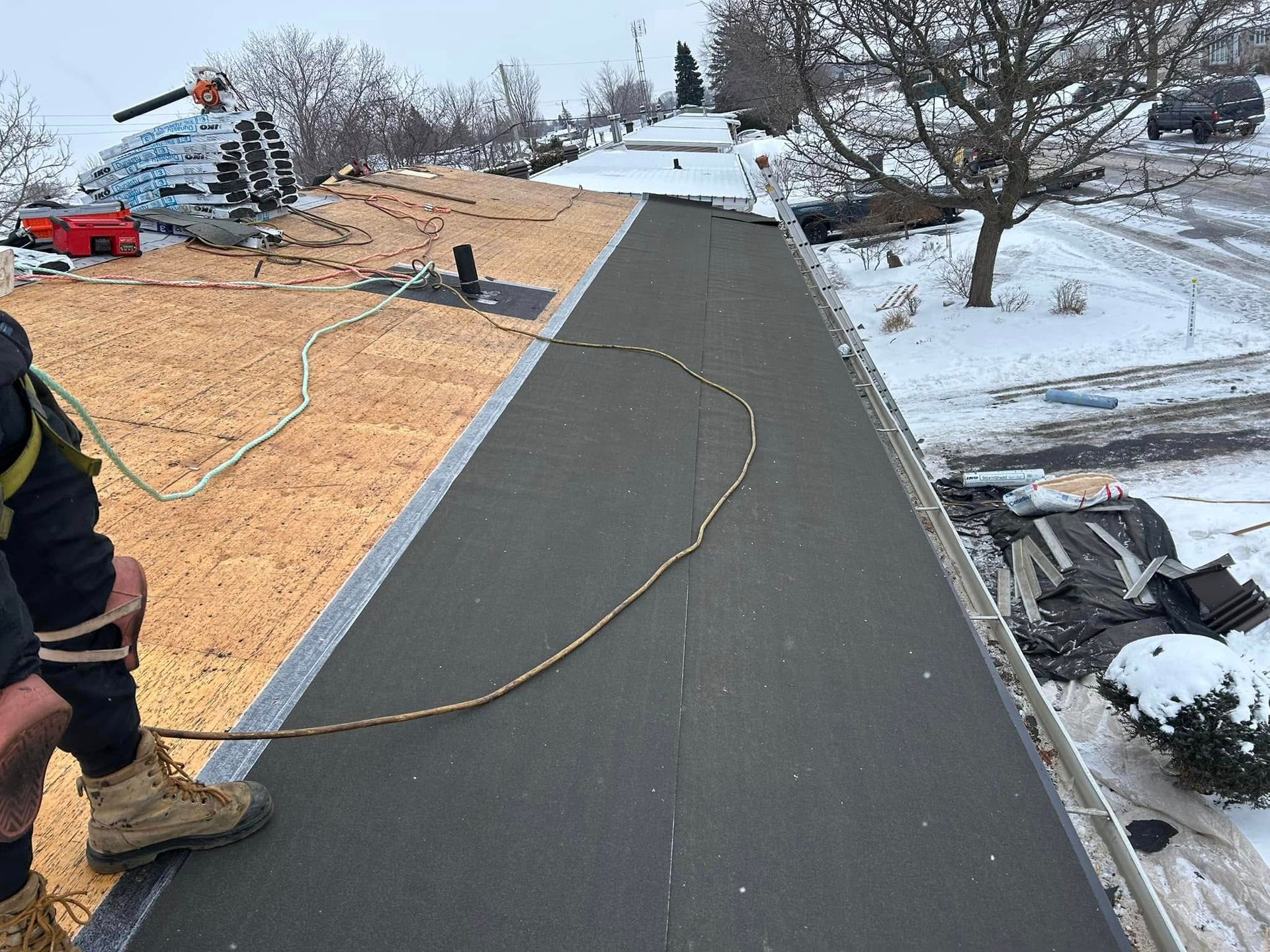 Un homme travaille sur un toit dans la neige.