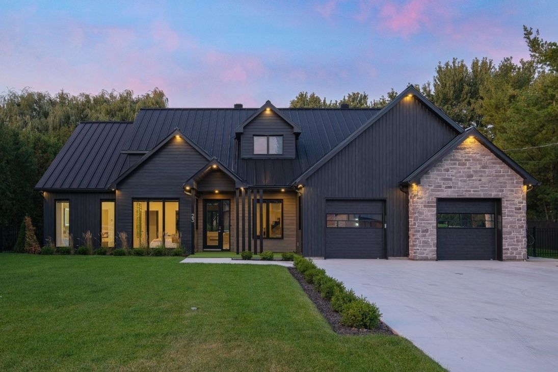 Maison grise moderne avec des éléments en pierre, une pelouse verte et une allée.