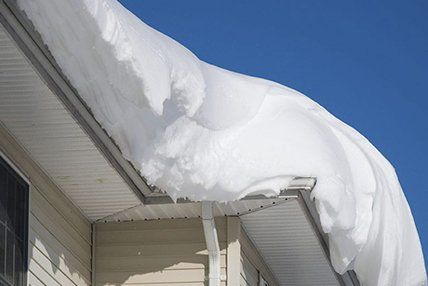 Il y a beaucoup de neige sur le toit d'une maison.