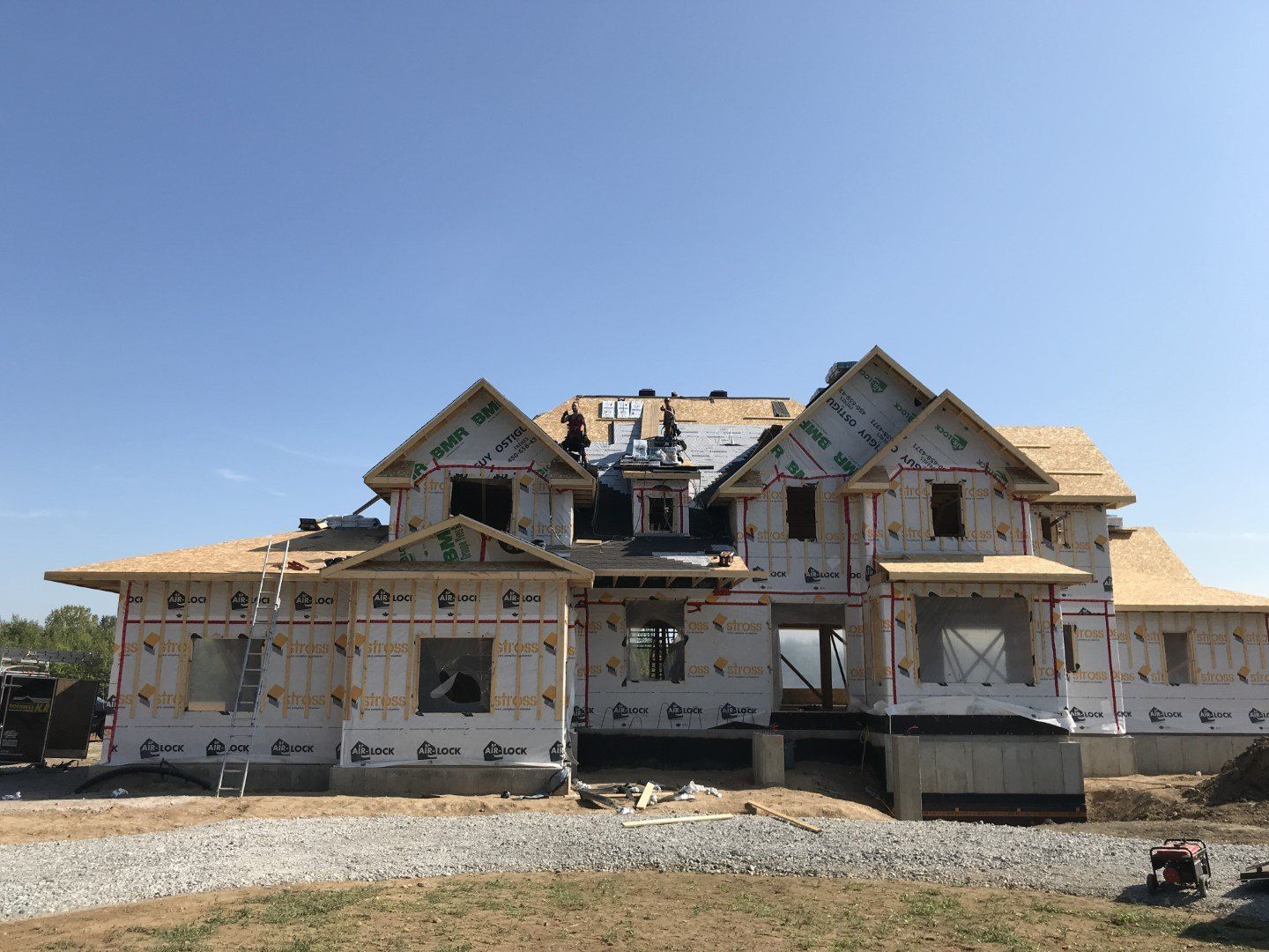 Une grande maison est en construction au milieu d'un champ de terre.