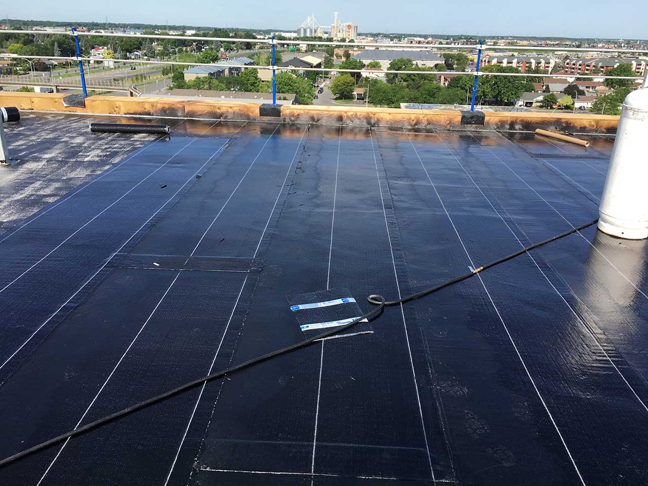 Un toit noir avec une cheminée blanche au-dessus.