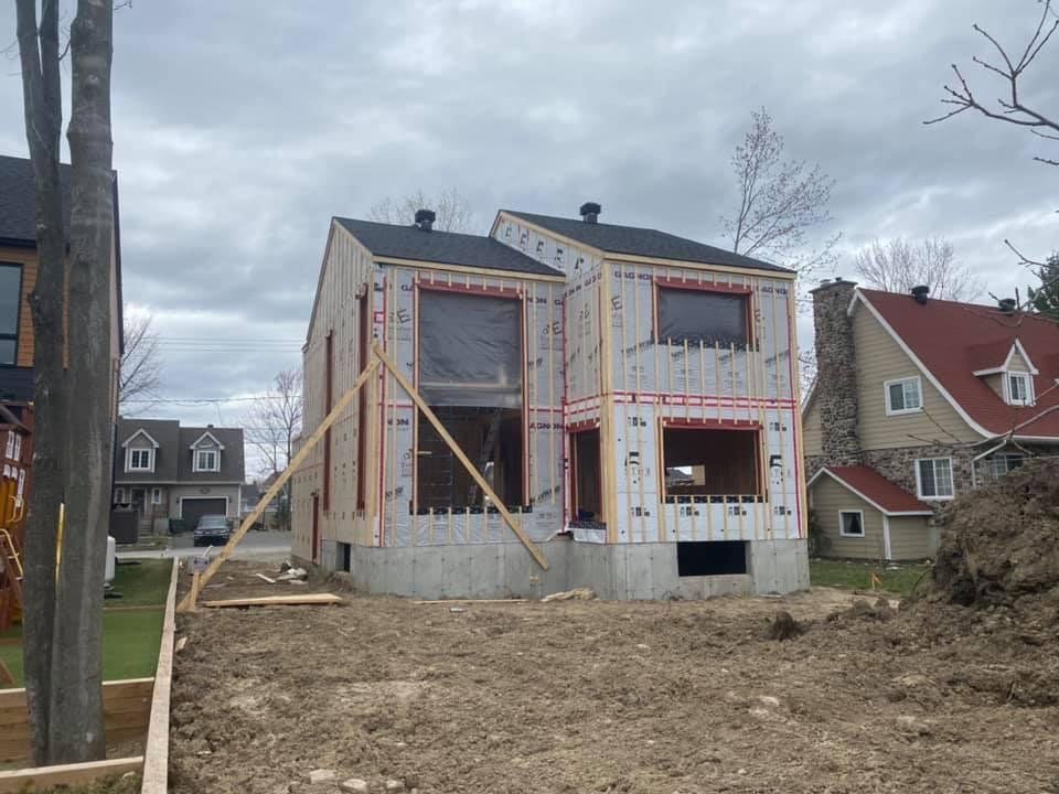 Une maison est en construction au milieu d'un champ de terre.