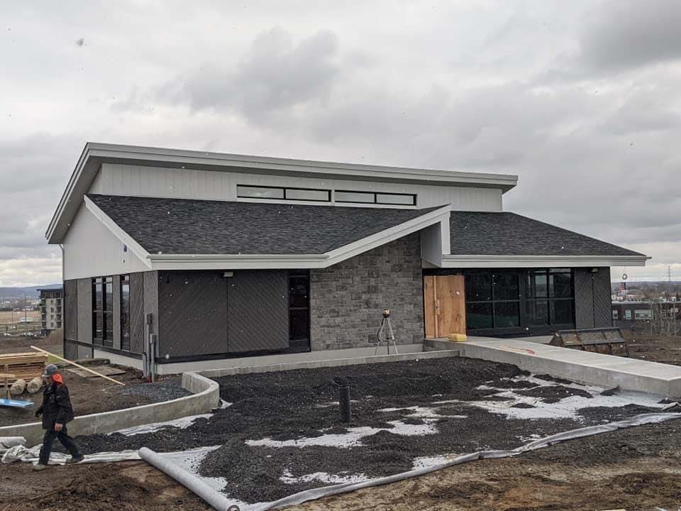 Un homme marche devant une maison en construction.