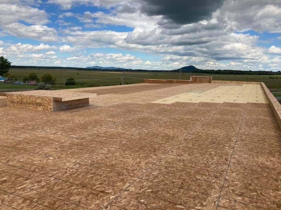 Un toit est en construction par une journée nuageuse avec une montagne en arrière-plan.