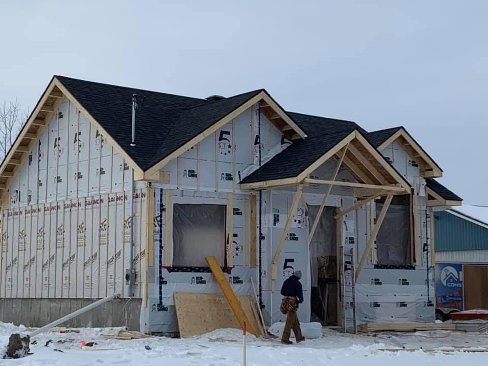 Un homme se tient devant une maison en construction