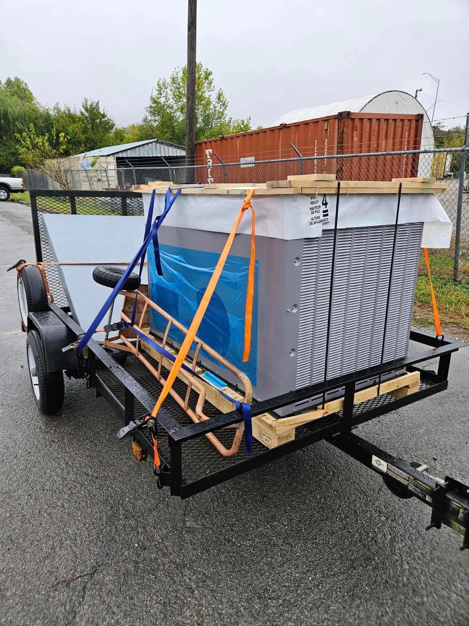 A trailer with a hot tub on it is parked on the side of the road.