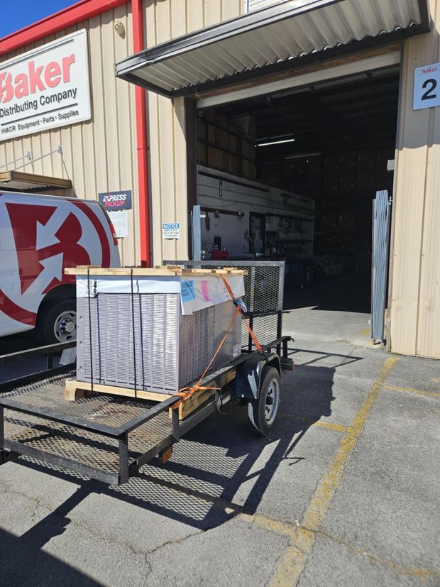 A trailer with a stack of boxes on it is parked in front of a building.