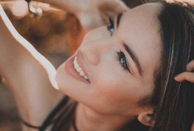 A close up of a woman smiling with her hand in her hair.