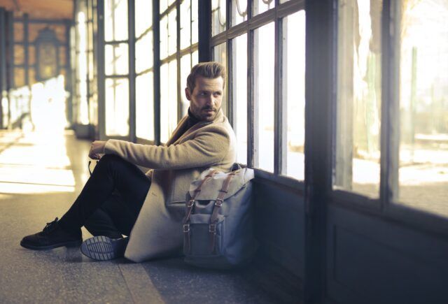 A man is sitting on the floor next to a window.