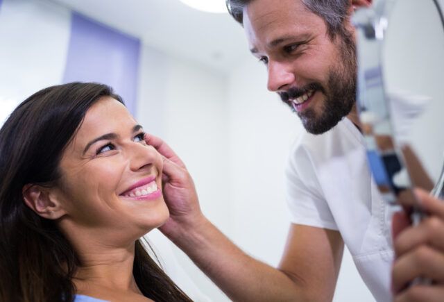 A man is looking at a woman 's face in a mirror.