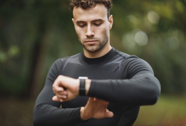 A man is looking at his smart watch on his wrist.