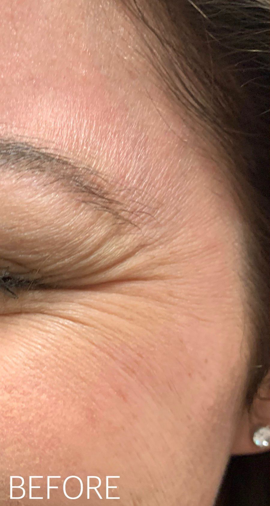 A close up of a woman 's face with wrinkles and earrings.