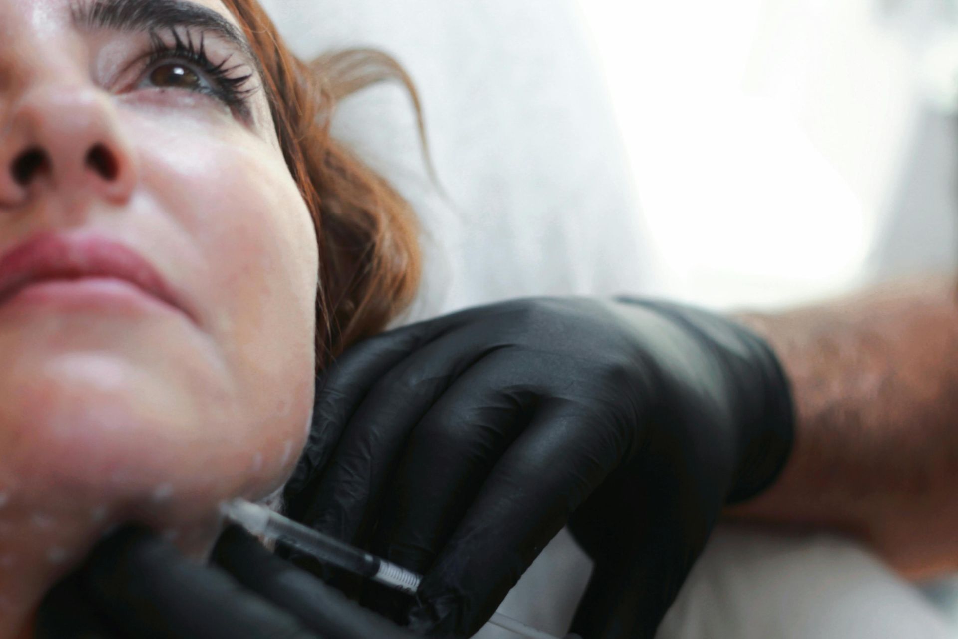 A woman is getting a botox injection in her lips.