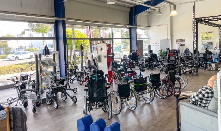Innenansicht des Sanitätshauses in Speyer für Mobilitätshilfen mit ausgestellten Rollstühlen und Gehhilfen. Sonnenlicht strömt durch große Fenster.