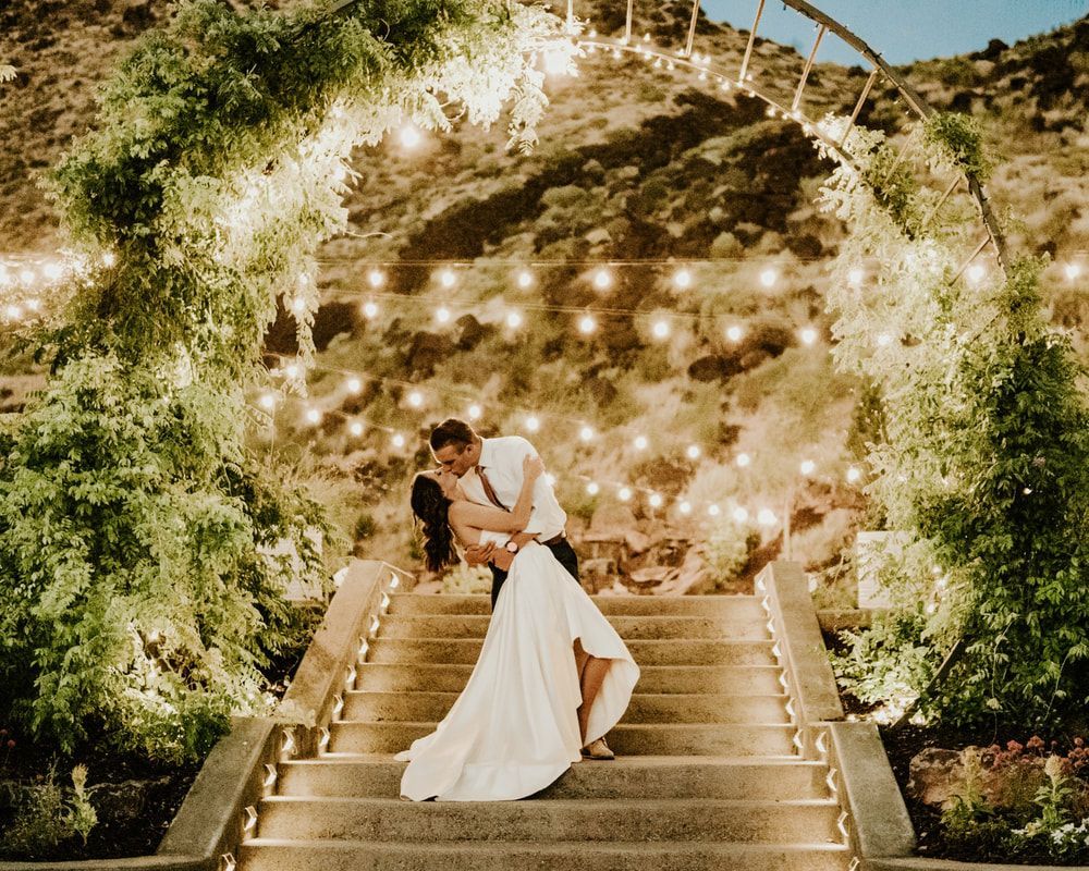 A bride and groom are kissing on a set of stairs.