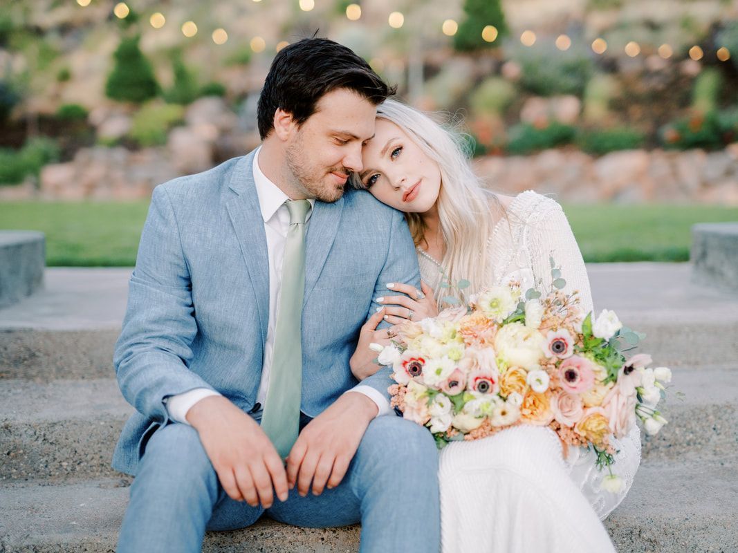 A bride and groom are sitting on a set of stairs with the bride holding a bouquet of flowers.
