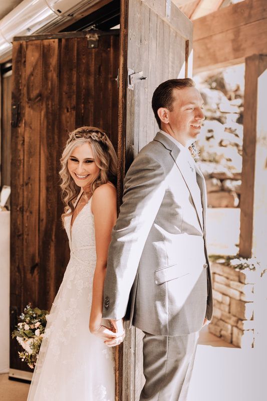 A bride and groom are standing next to each other in front of a wooden door.