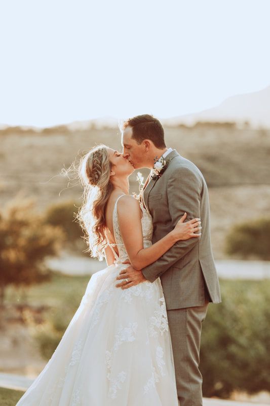 A bride and groom are kissing on their wedding day.