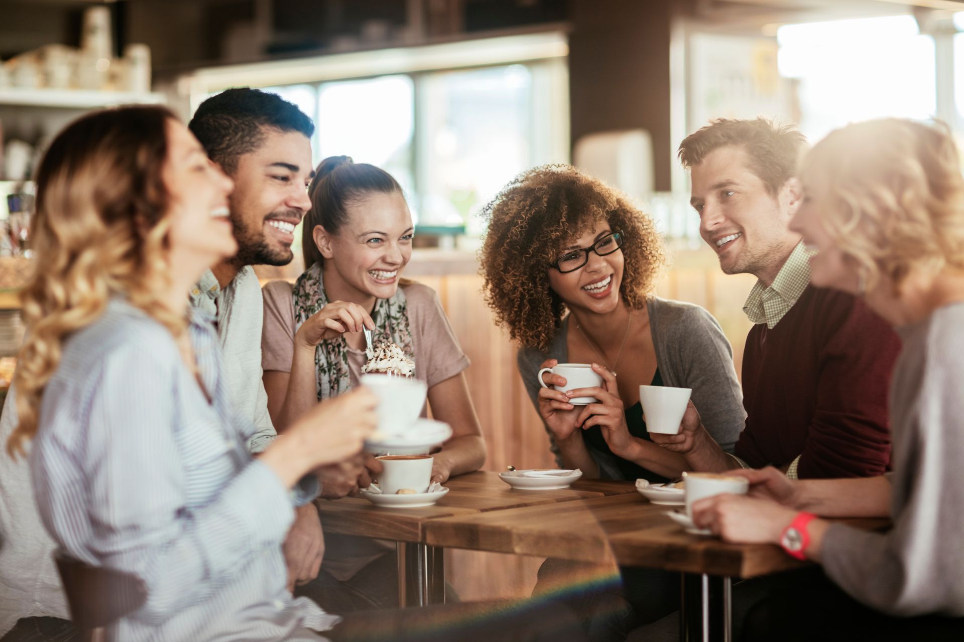 Group of friends smiling and drinking coffee at a cafe.
