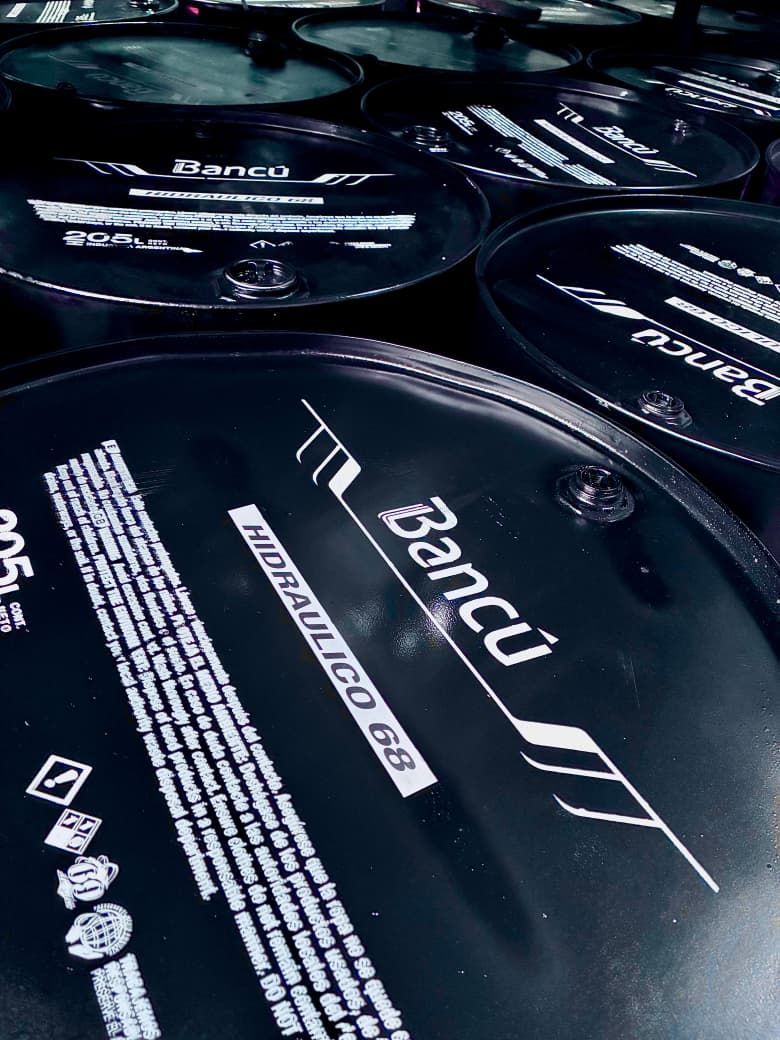 Bidones de aceite negros con texto blanco, marca