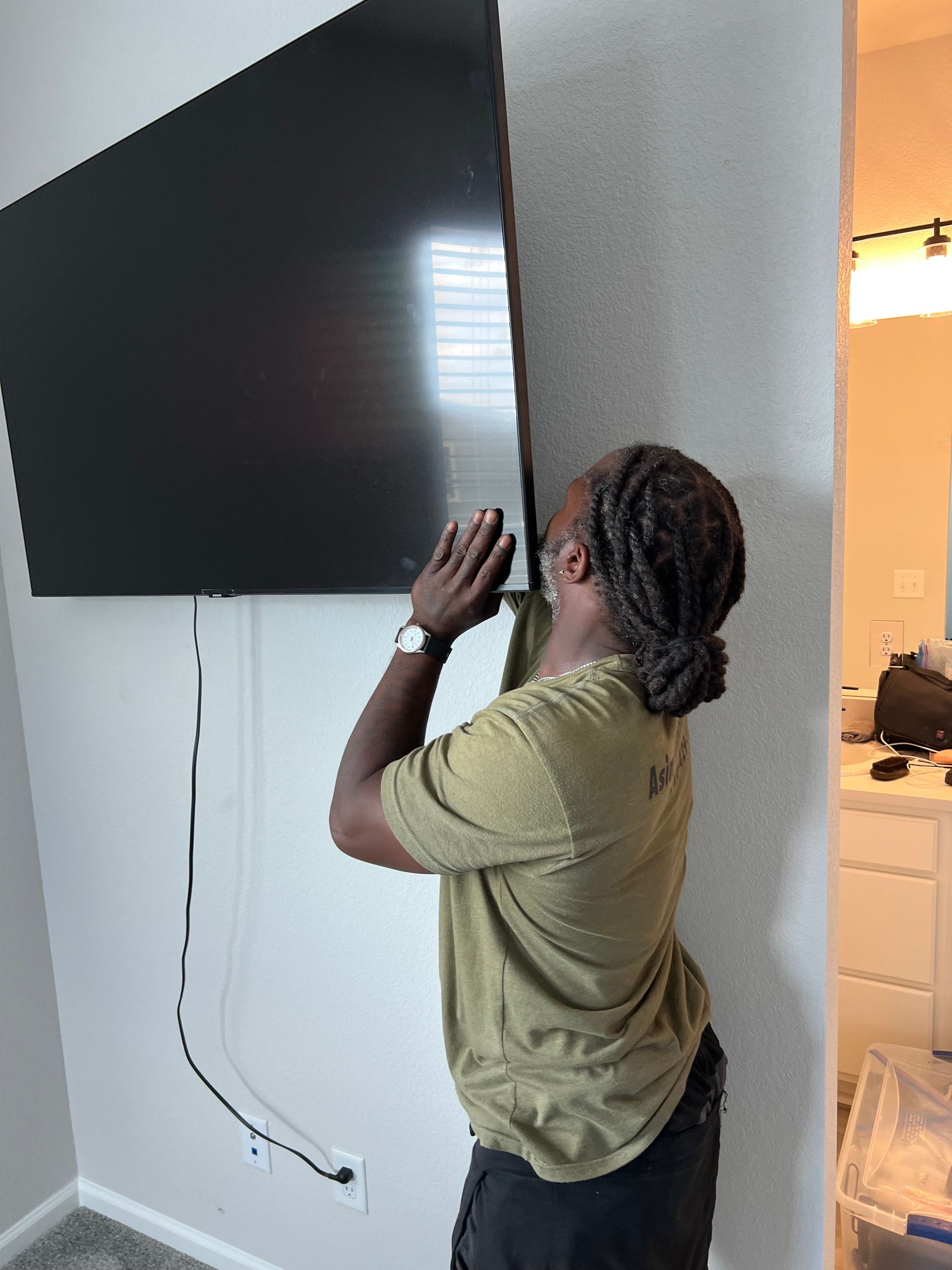 A man is installing a flat screen tv on a wall.