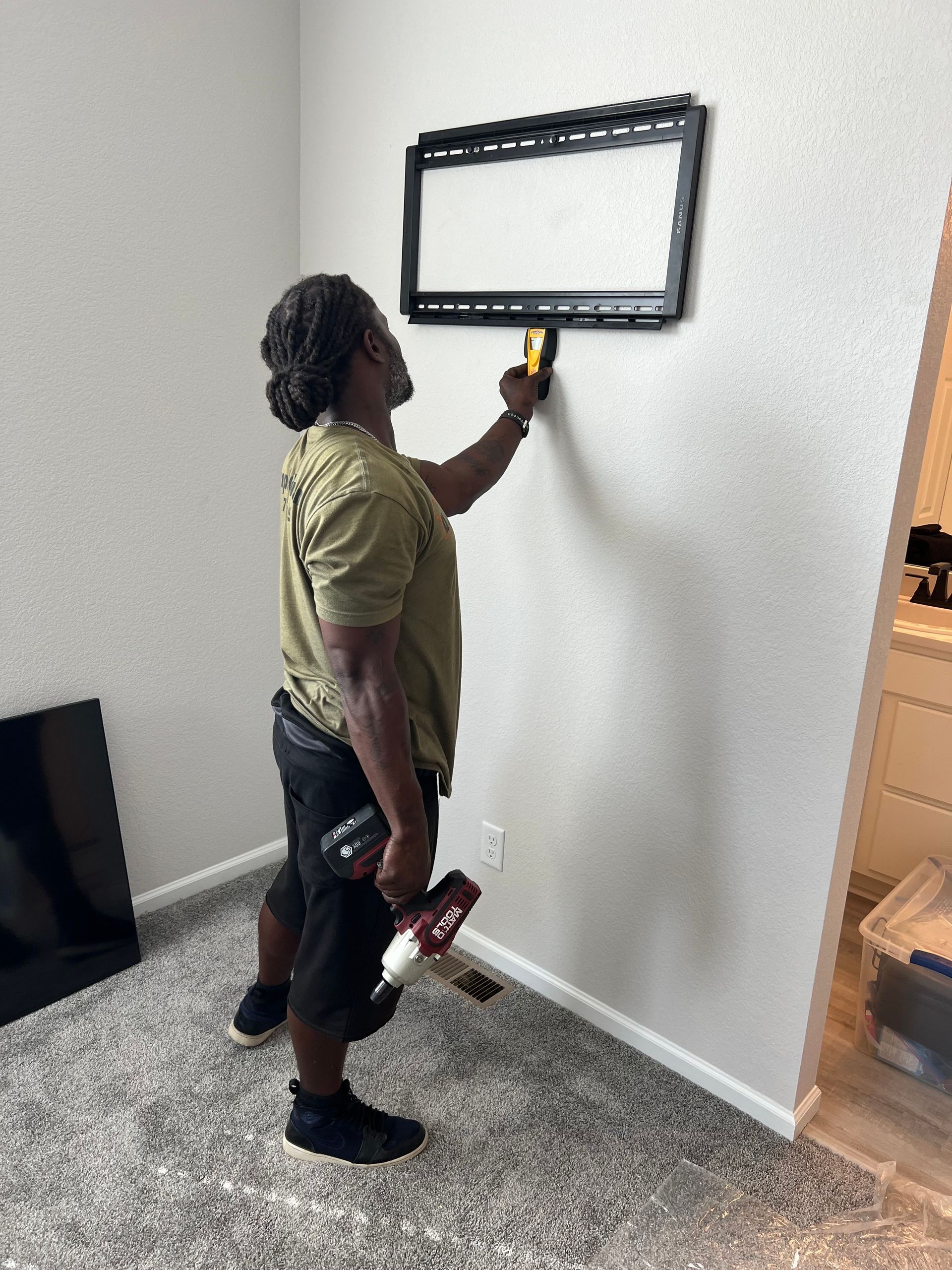 A man is installing a flat screen tv on a wall.