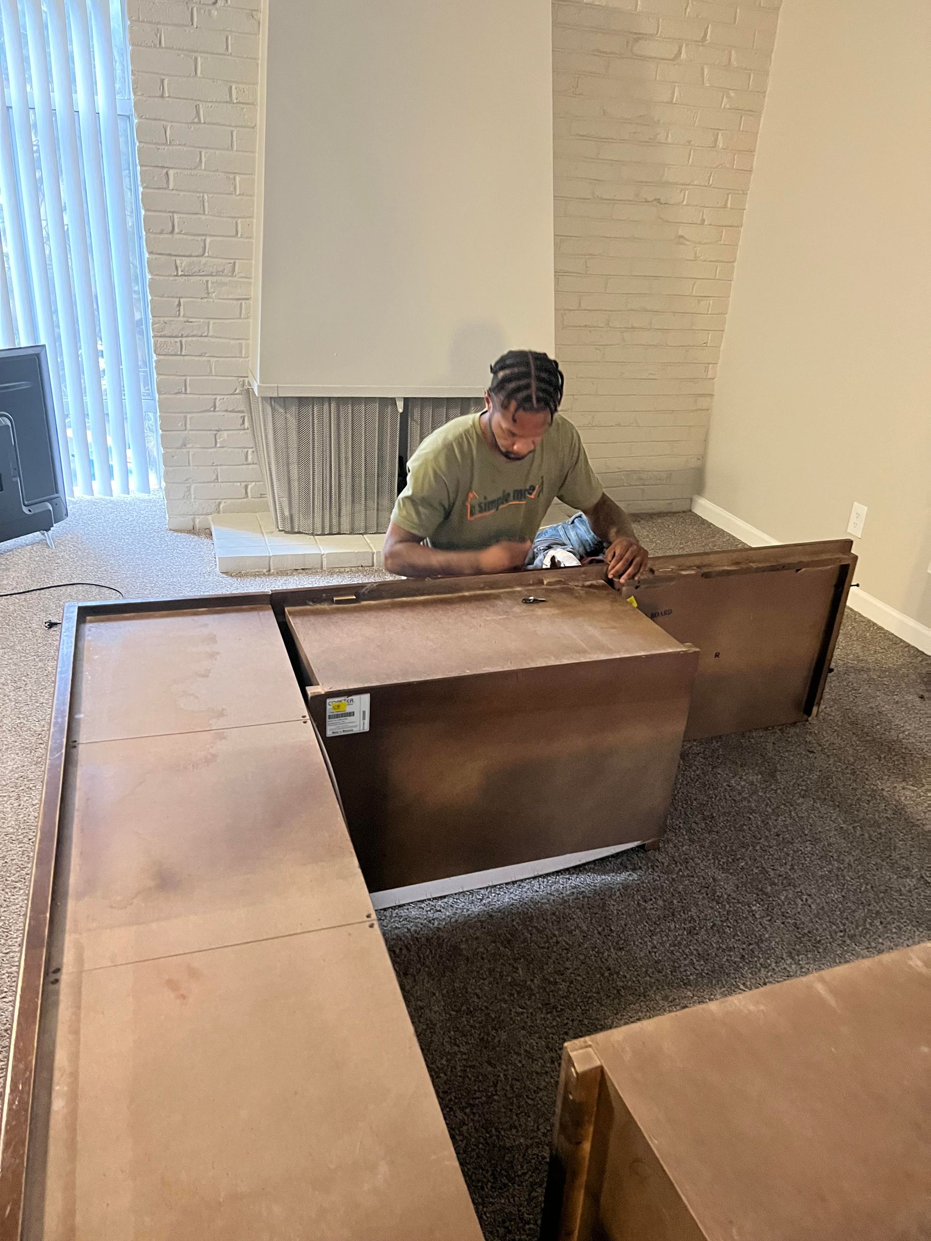 A man is working on a wooden table in a living room.