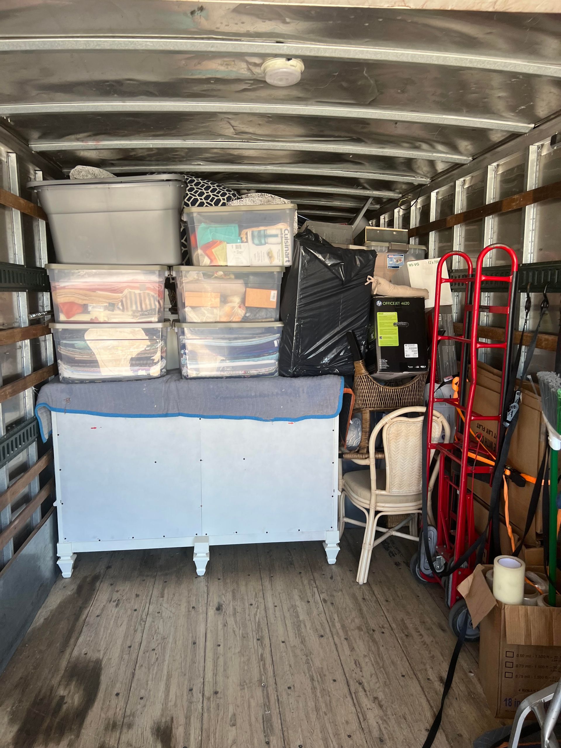 The inside of a moving truck filled with furniture and boxes.