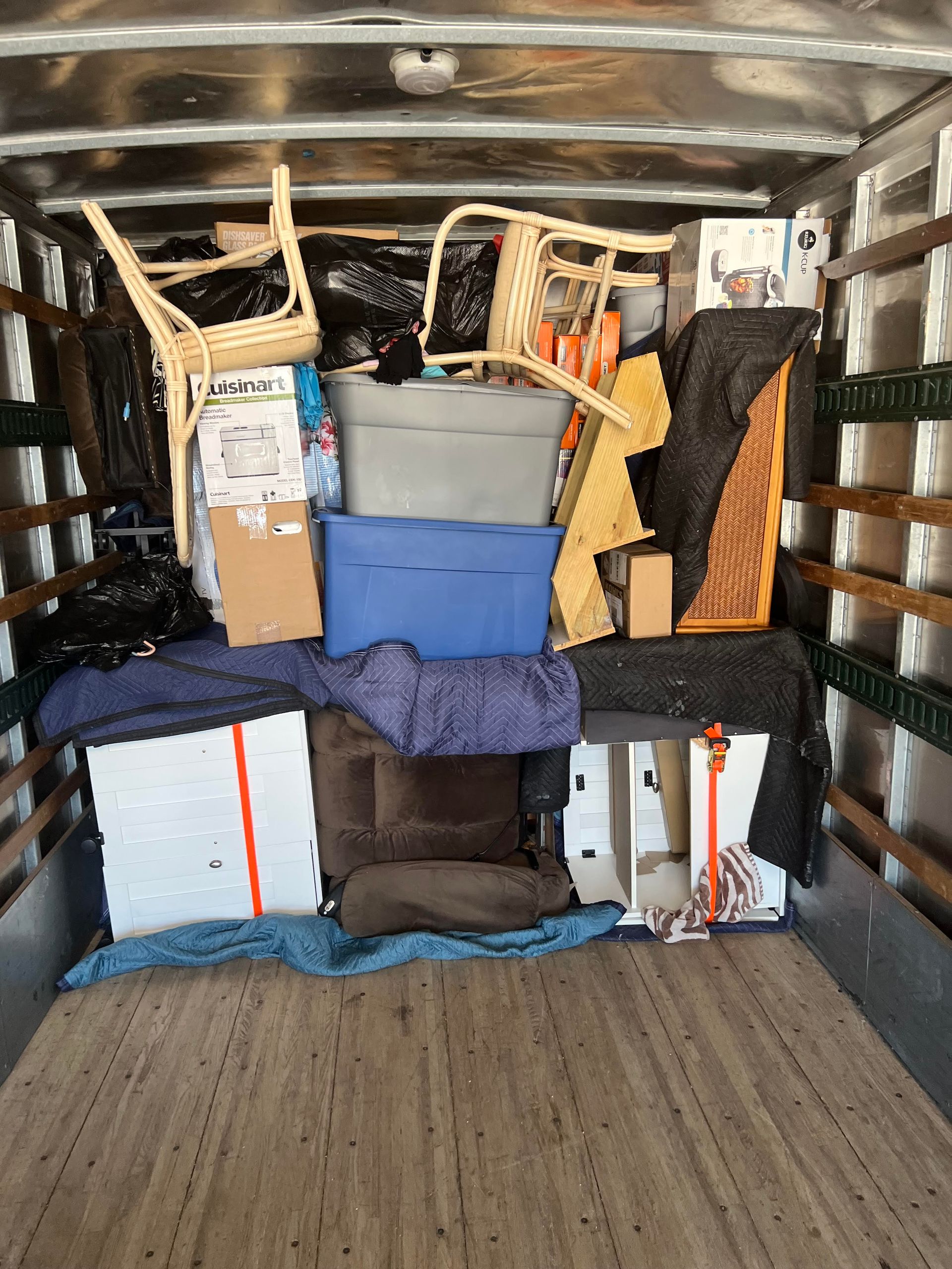 The back of a moving truck is filled with furniture and boxes.
