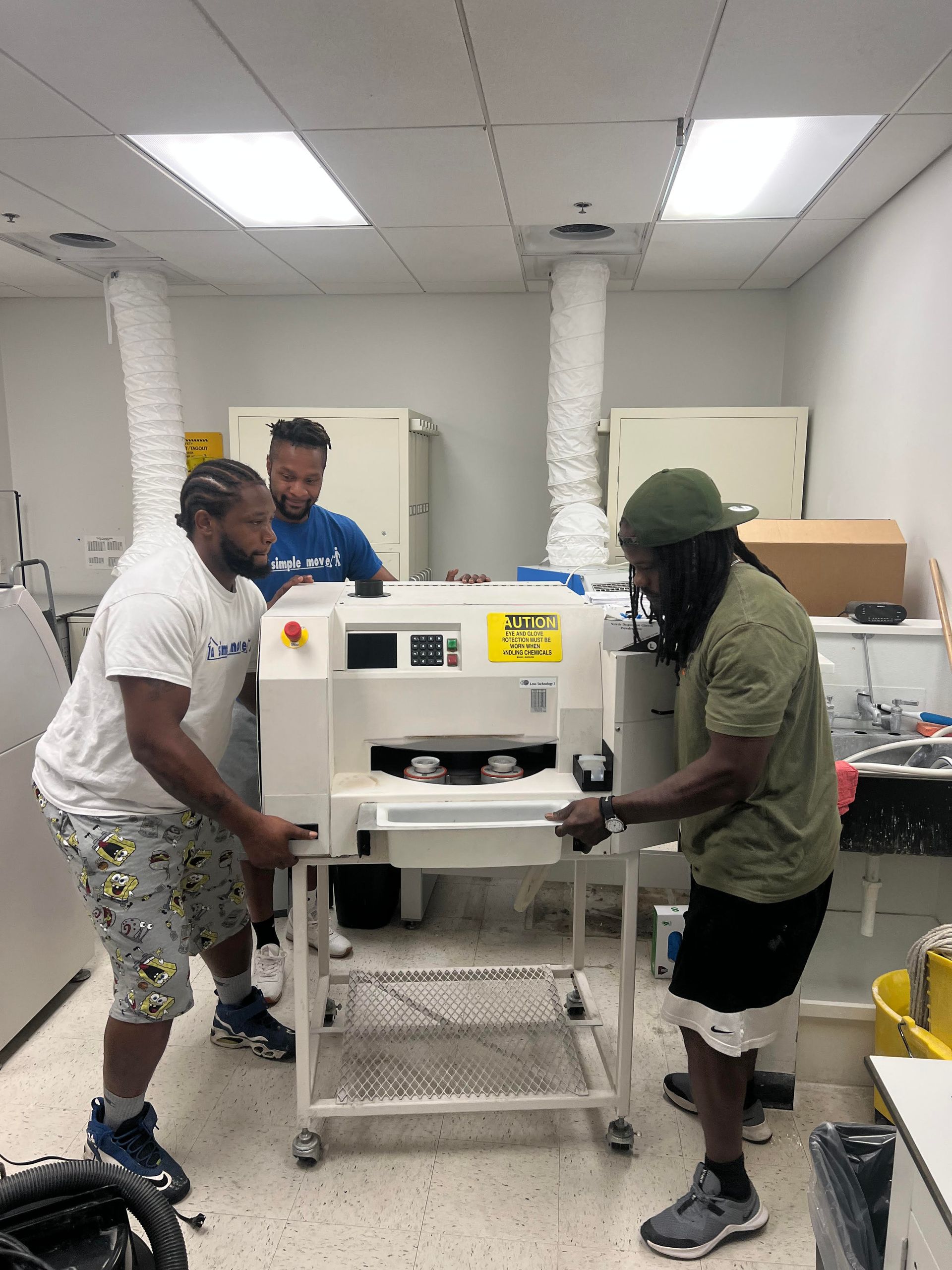 Three men are working on a machine in a room.