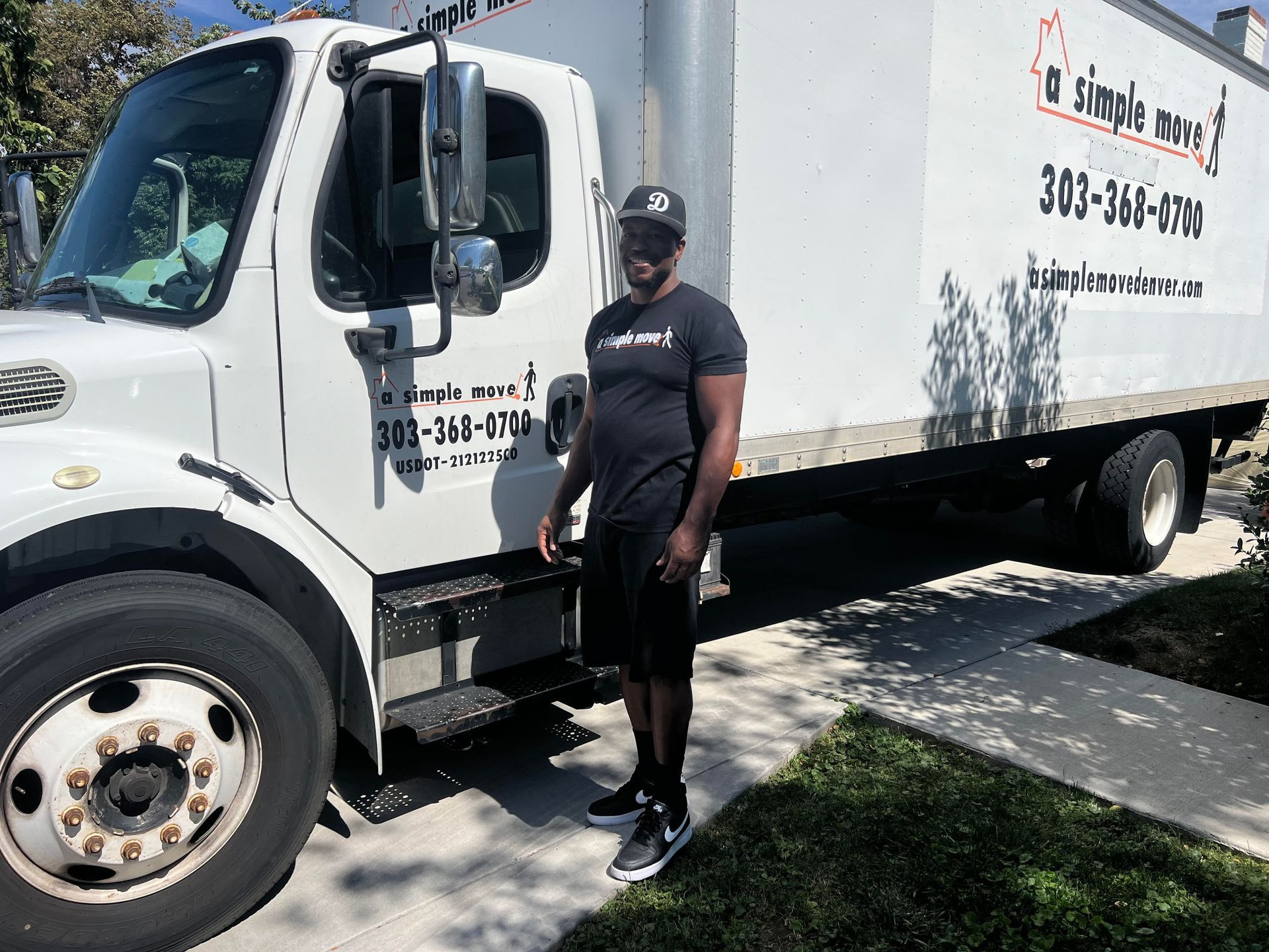 A man in a black shirt is standing in front of a moving truck.